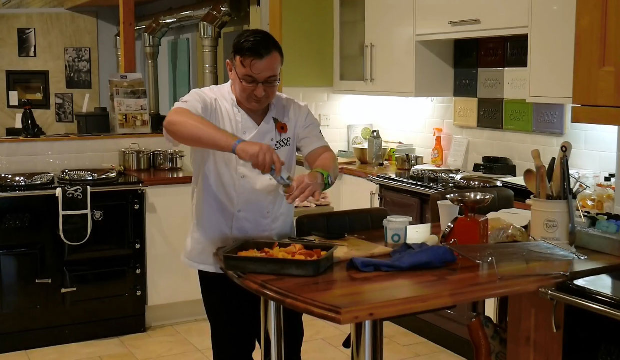 Dan Blewitt seasoning food in front of an ESSE range cooker